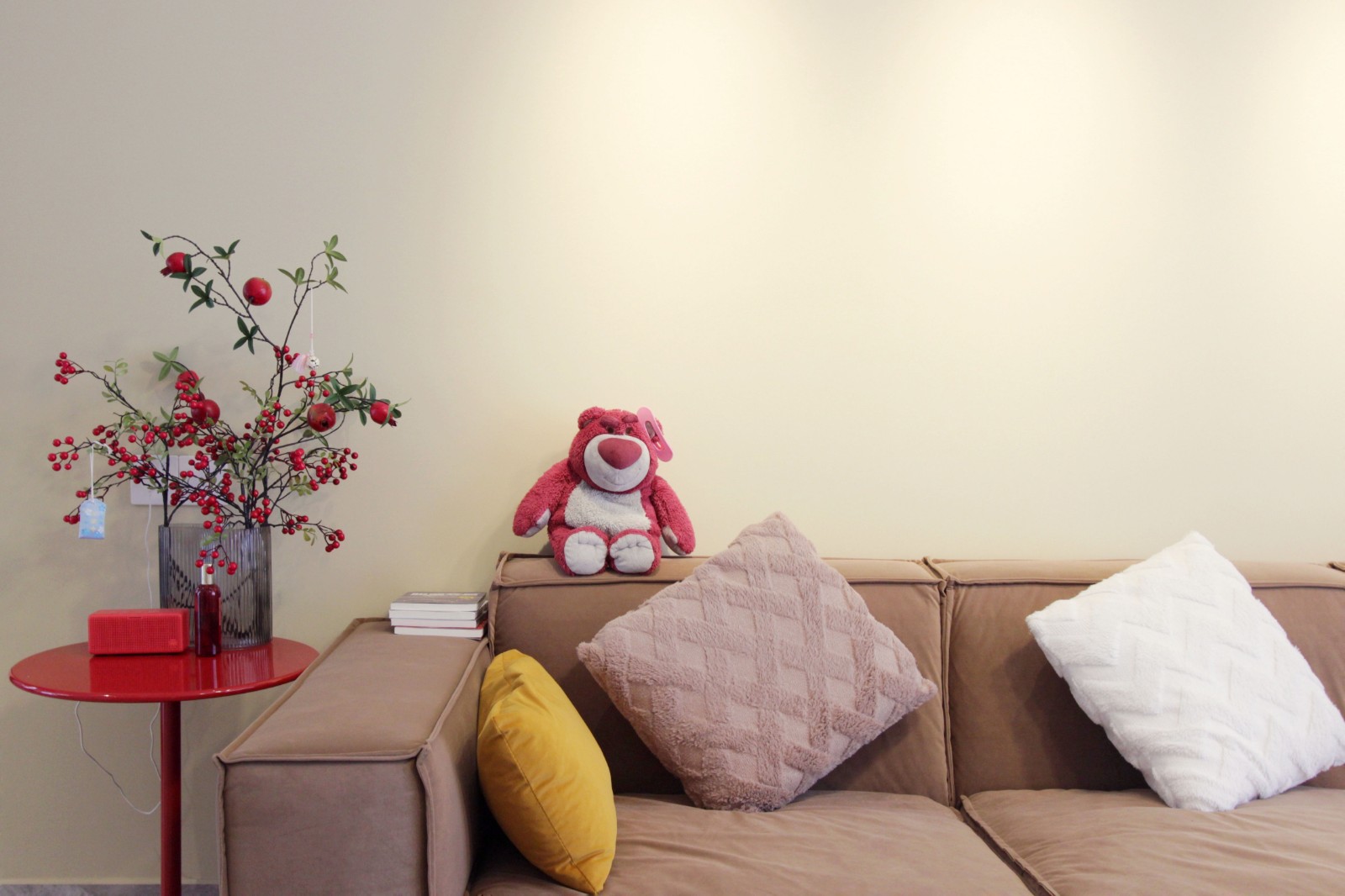 褐色布艺沙发与米色背景墙搭配,温暖舒适,一边放上红色边几,给空间