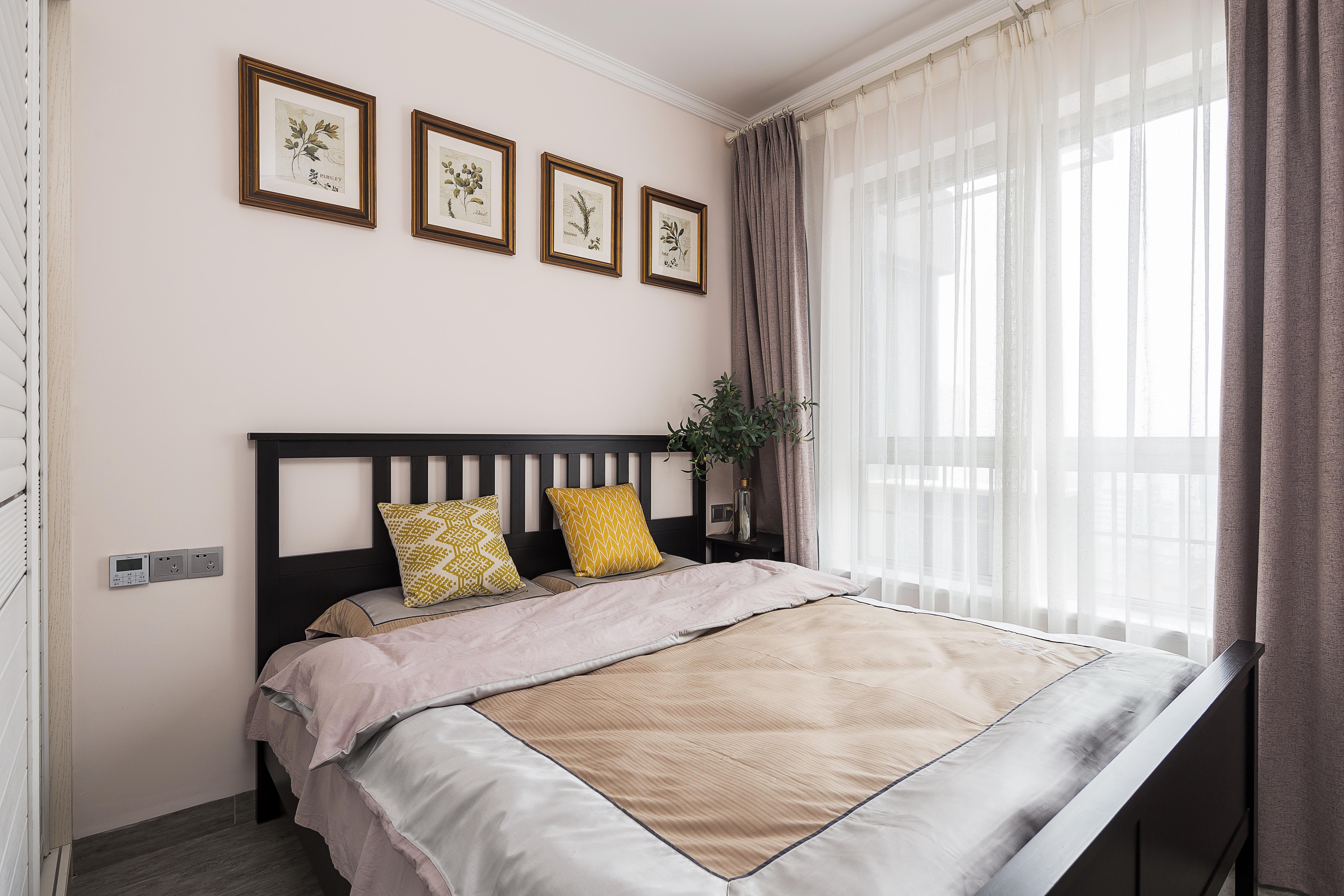 次卧浅粉色乳胶漆墙面点缀几幅绿植装饰画作床背景黑色简约大床与小巧