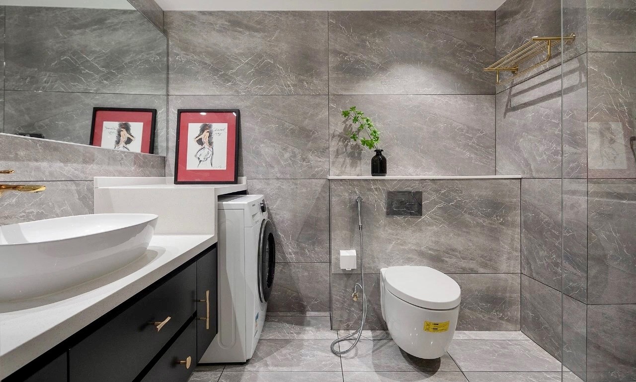 卫生间墙地通铺灰色石纹砖,错落台盆柜预留洗衣机位置,大面的墙镜扩大