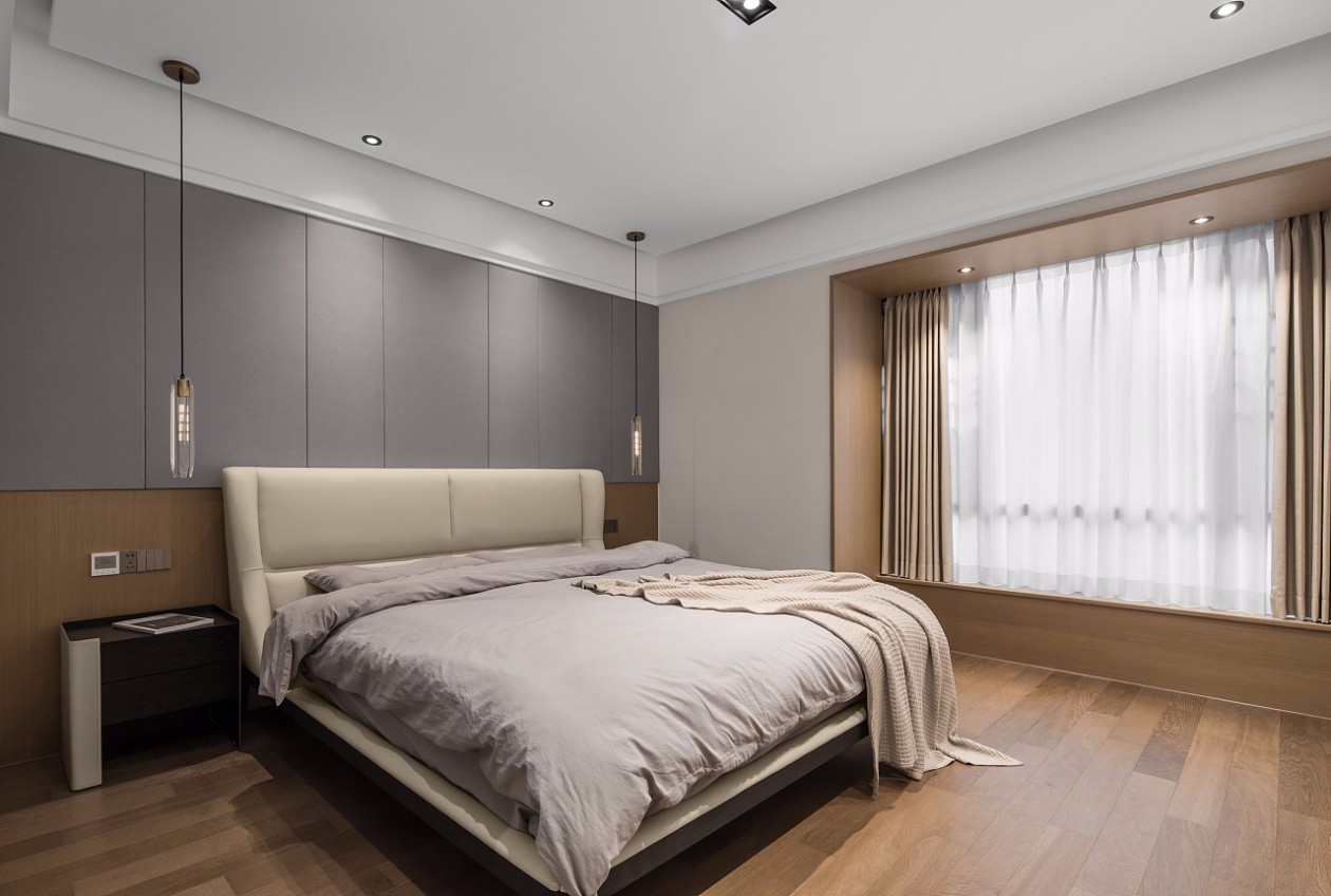 主卧暖灰色的硬包浮绕与木饰面之上,犹如山间烟雨的灰青从林间飘然而