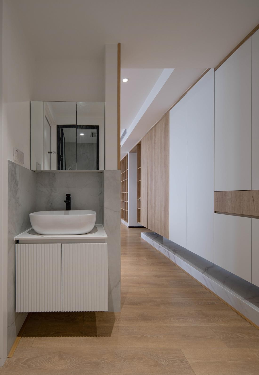 木质的温润从地面延伸至半高位置,上部空间留白搭配奶白的软装配饰