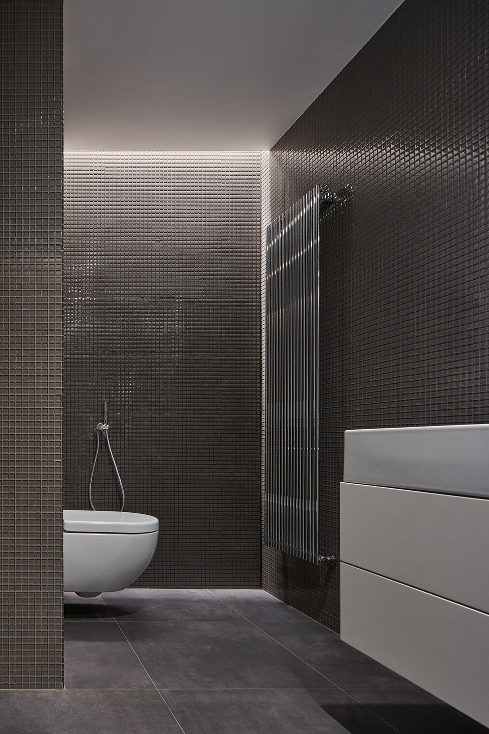 儿童浴室主要由玻璃马赛克墙面和浅灰色的地砖组成.