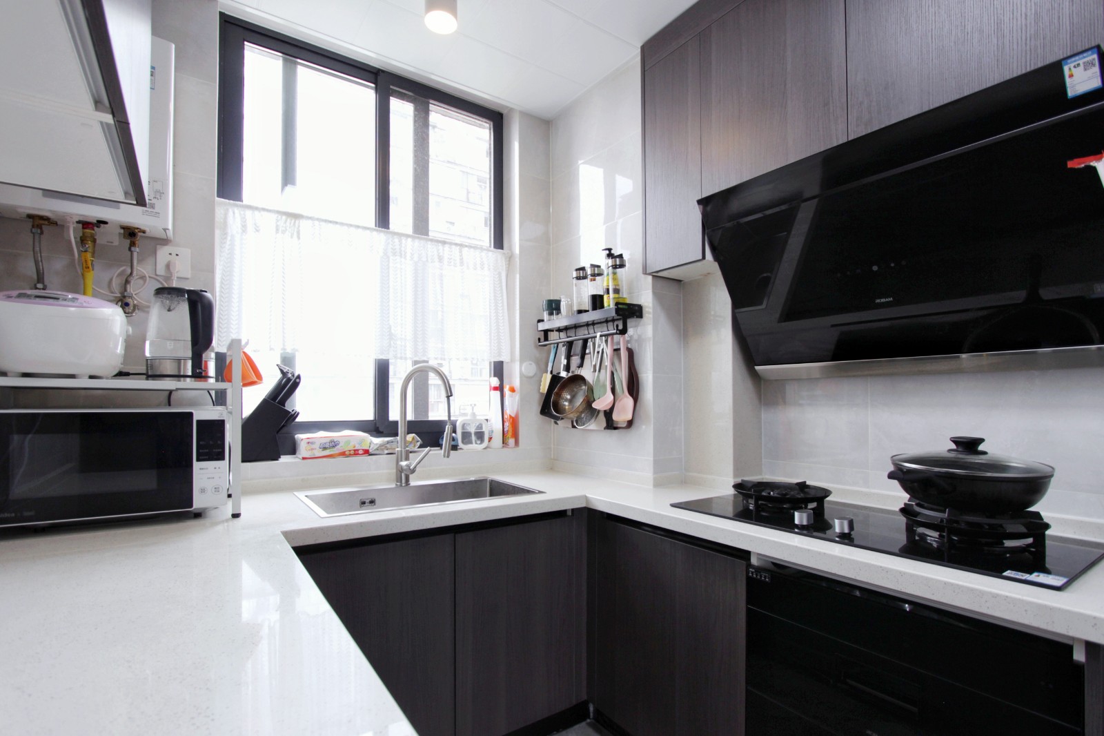 厨房整体为黑白灰色调,黑色橱柜搭配的是白色台面与灰色大理石地砖