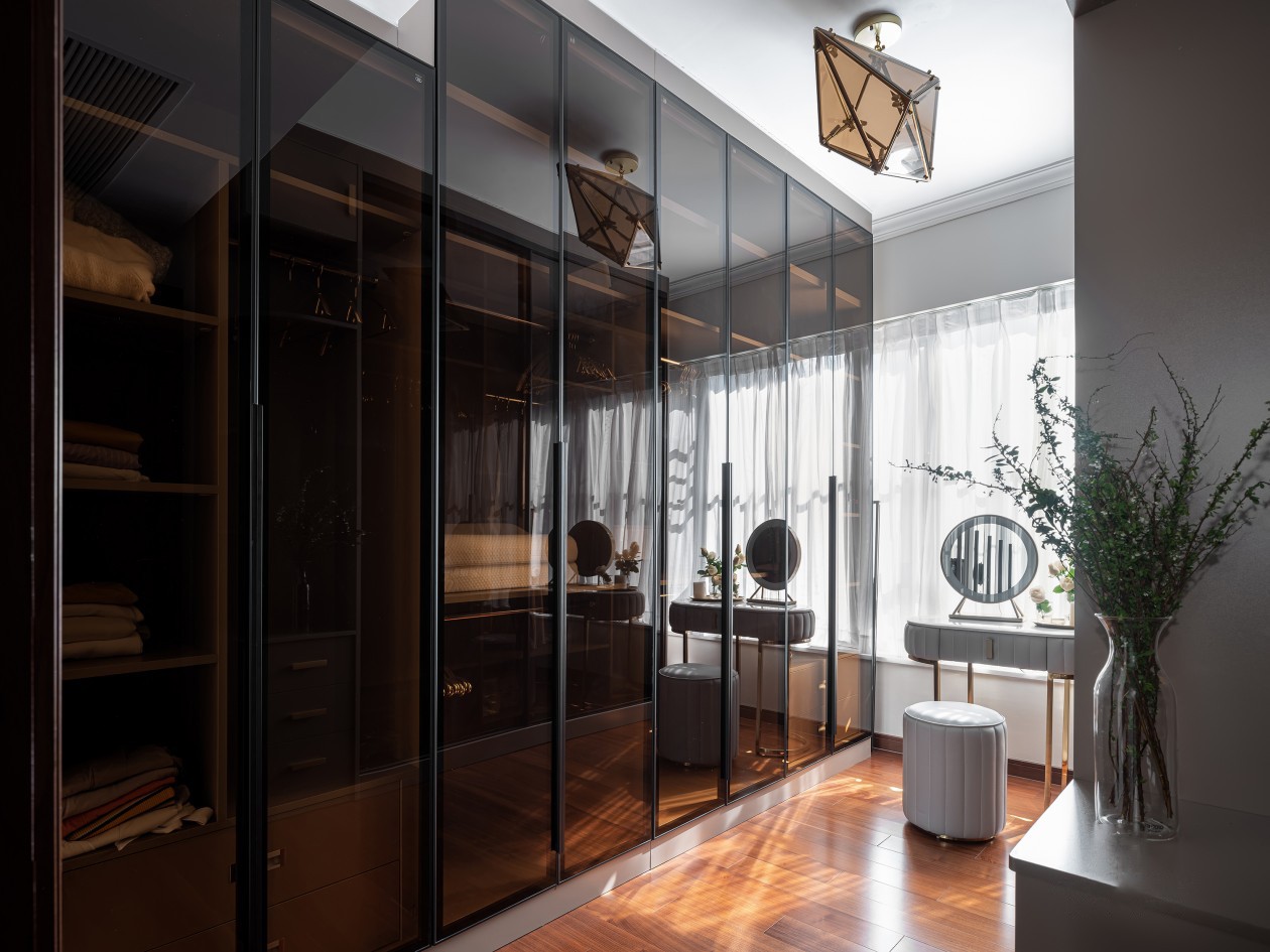 衣柜高度做了分层处理,整体顶天立地的茶色玻璃柜门,使空间更加通透不